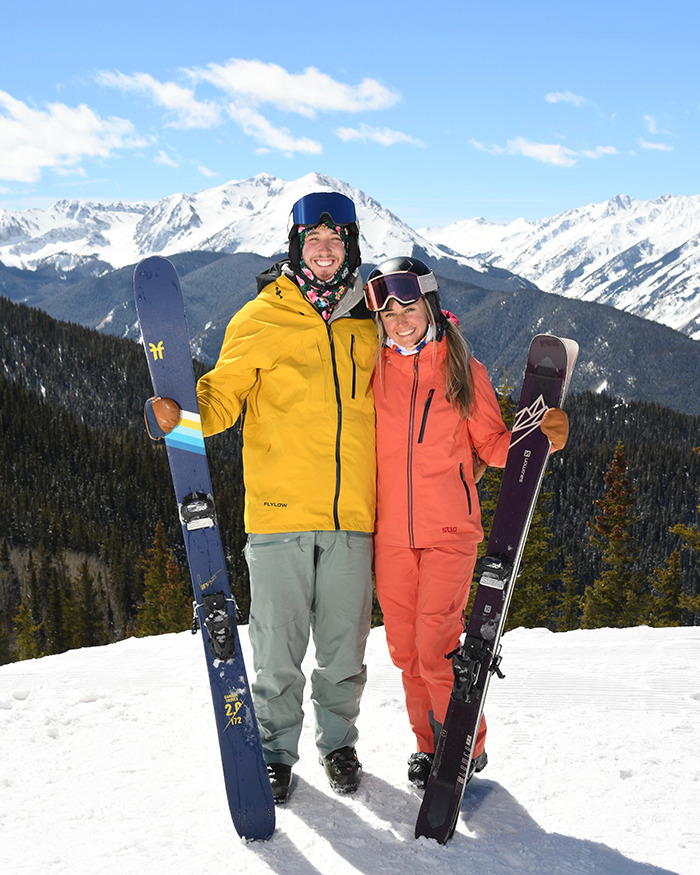Newlywed couple smiling on snowy mountain with skis, enjoying honeymoon before tragedy near ankle-deep water.
