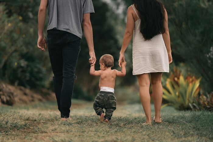 Family holding baby’s hands walking outdoors, illustrating something totally normal in your country that shocks Americans.