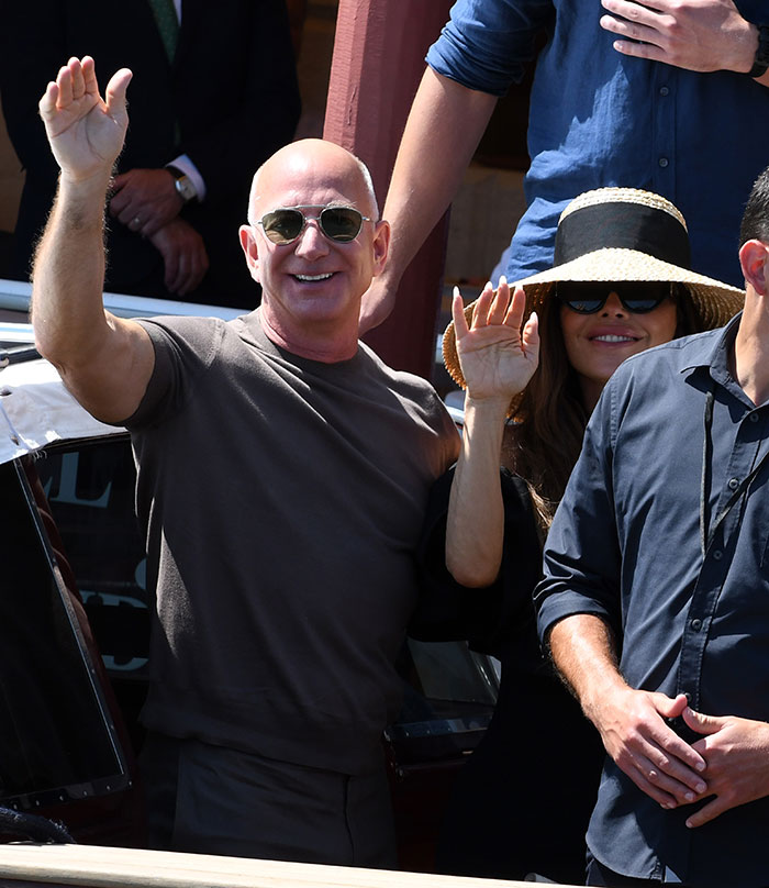 Jeff Bezos and Lauren S&aacute;nchez waving while attending a celebrity event after weekend wedding partying.