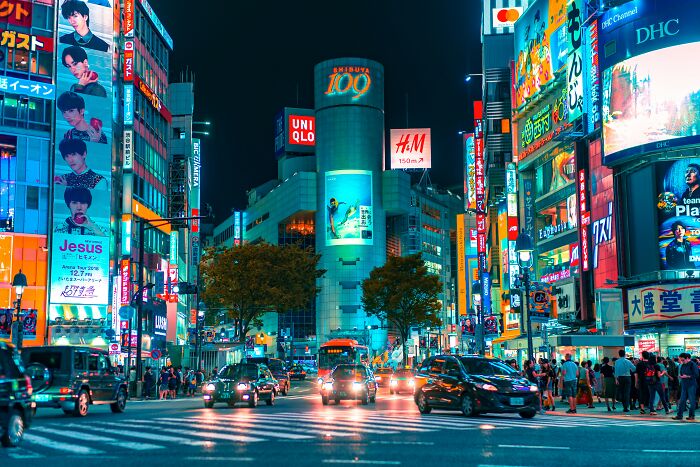Bustling Shibuya street at night with bright neon signs, showcasing the challenges of being big in Japan in real life.
