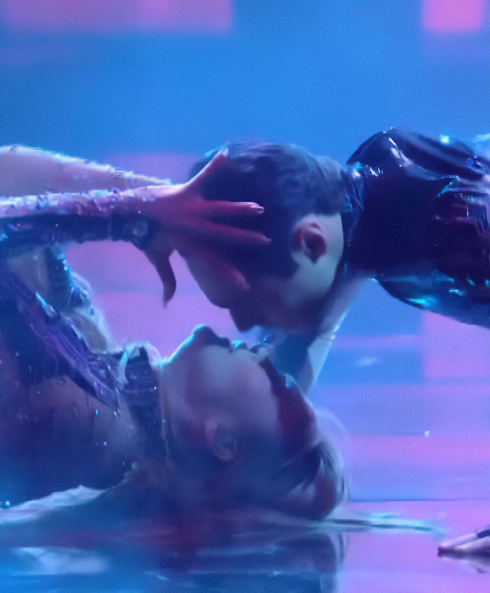 Jennifer Lopez performing a dramatic dance move on stage, wearing a glittery outfit under concert lighting.