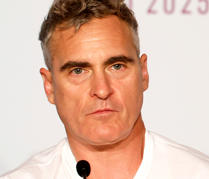 Close-up of a man with unique facial features at a press event, highlighting celebrity body anomalies and distinct traits.