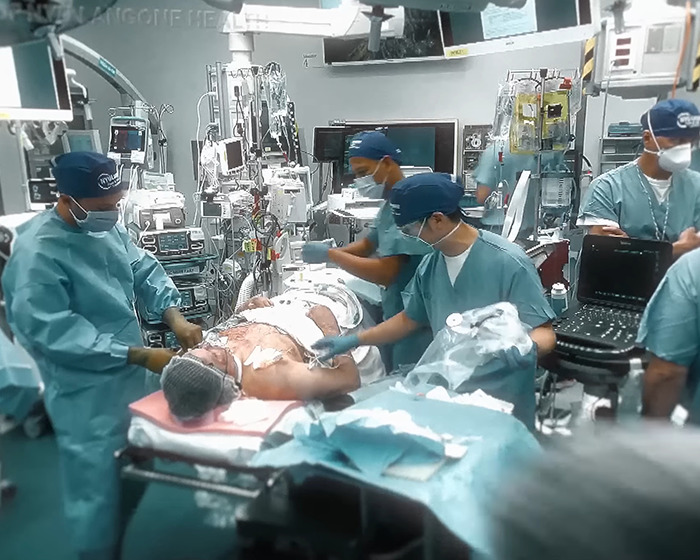 Medical team performing complex face transplant surgery on patient in operating room with advanced medical equipment and monitors Medical team performing complex face transplant surgery on patient in operating room with advanced medical equipment and monitors