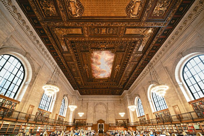 Grand historic library interior with ornate ceiling, large arched windows, and rows of bookshelves showcasing stunning bookstores and libraries.