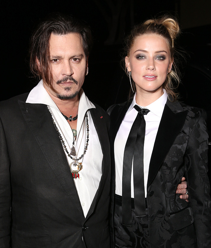 Johnny Depp and Amber Heard posing together at a formal event, dressed in black and white outfits.