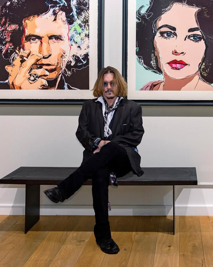 Johnny Depp sitting on a bench in front of colorful portraits, highlighting Amber Heard trial and his agent controversy.