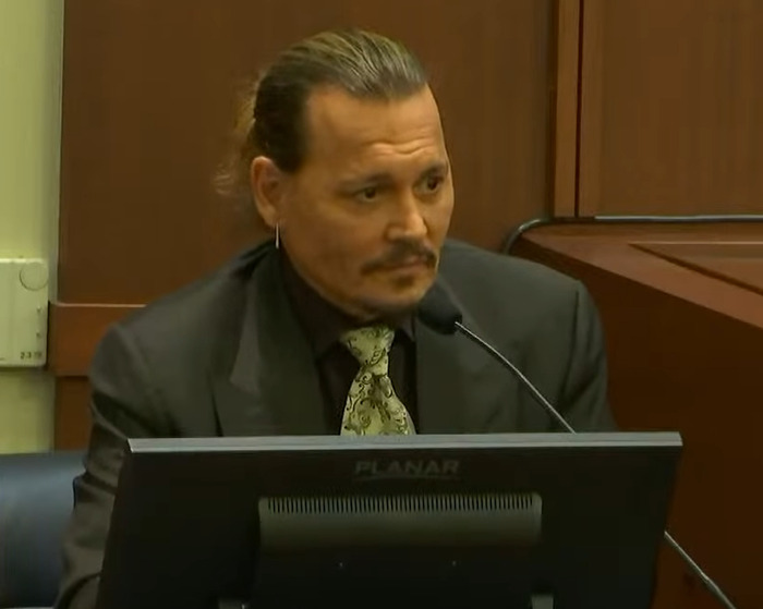 Johnny Depp trial juror speaking in courtroom, wearing suit and patterned tie during testimony reveal courtroom secrets.