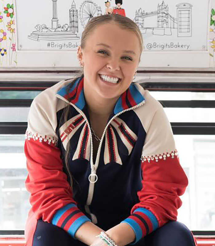 Young woman smiling in a colorful jacket, representing JoJo Siwa hits back after Miley Cyrus Pride joke backlash. Young woman smiling in a colorful jacket, representing JoJo Siwa hits back after Miley Cyrus Pride joke backlash.