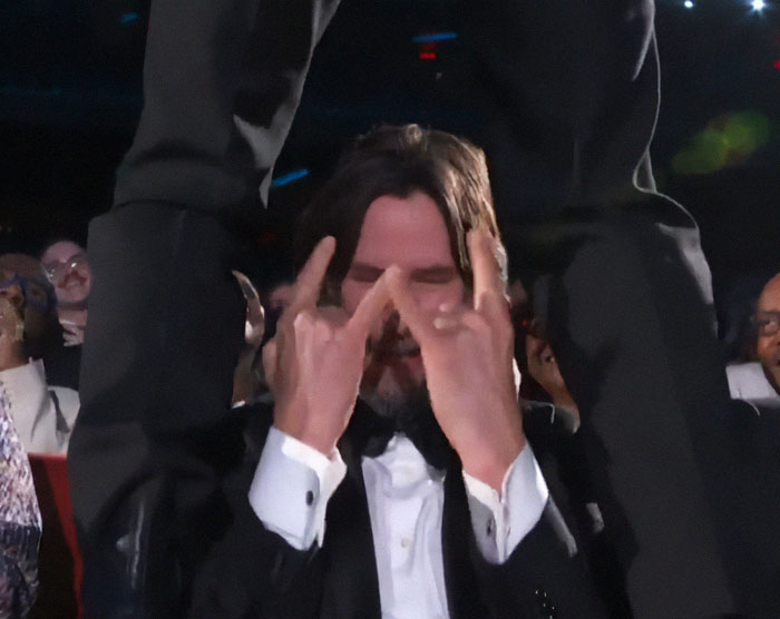 Keanu Reeves reacting while Jonathan Groff straddles him live at the 2025 Tony Awards, capturing a memorable moment.