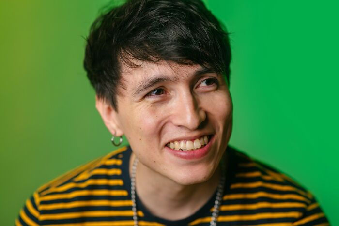 Young man smiling and looking away, showing behaviors that may indicate someone is insecure in a casual setting.