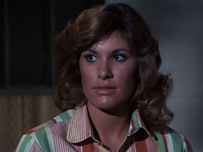 Beloved 70s TV actress with wavy hair and striped shirt looking off-camera in a dimly lit indoor setting Beloved 70s TV actress with wavy hair and striped shirt looking off-camera in a dimly lit indoor setting