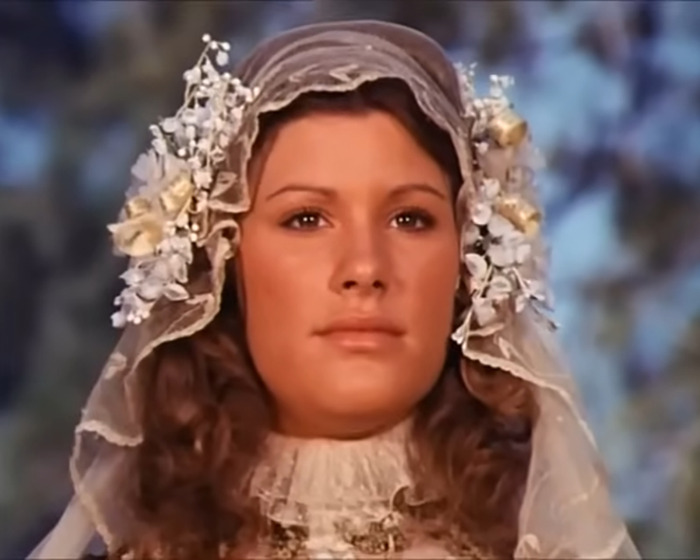 Beloved 70s TV actress in vintage bridal attire with floral headpiece, looking serene against a blurred natural background. Beloved 70s TV actress in vintage bridal attire with floral headpiece, looking serene against a blurred natural background.