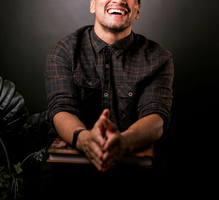 Smiling man in a plaid shirt laughing during a casual moment, representing male coworkers in the workplace setting.