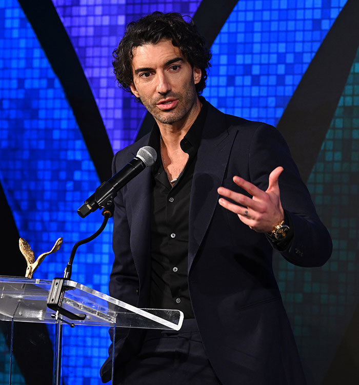 Actor Justin Baldoni speaking at a podium during an event related to his $400M lawsuit being dismissed.