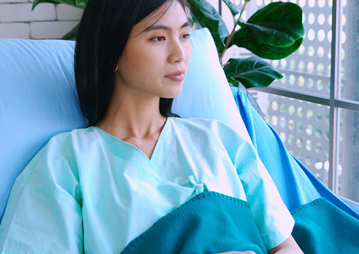 New mom in hospital gown resting by the window, reflecting quietly in a calm NICU environment. New mom in hospital gown resting by the window, reflecting quietly in a calm NICU environment.