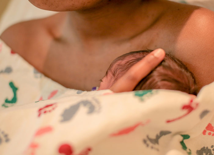 New mom holding newborn wrapped in a blanket, showcasing a tender moment related to NICU and malicious compliance. New mom holding newborn wrapped in a blanket, showcasing a tender moment related to NICU and malicious compliance.