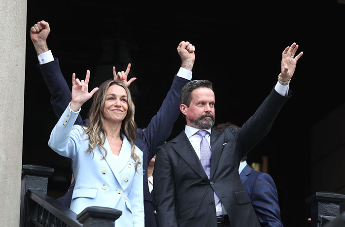 Karen Read celebrating acquittal verdict, raising hands with supporters outside courthouse after slaying cop boyfriend trial.