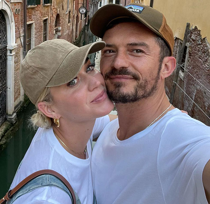 Katy Perry and Orlando Bloom wearing caps, posing for a close selfie in a narrow Venice canal alley. Katy Perry and Orlando Bloom wearing caps, posing for a close selfie in a narrow Venice canal alley.