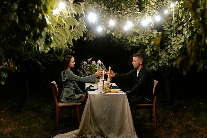 Couple sharing a romantic dinner outdoors under string lights, illustrating hooking up with a friend’s parent scenario.