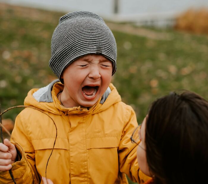 Young child in yellow jacket and striped hat making a face outdoors, illustrating weird things couples started doing.
