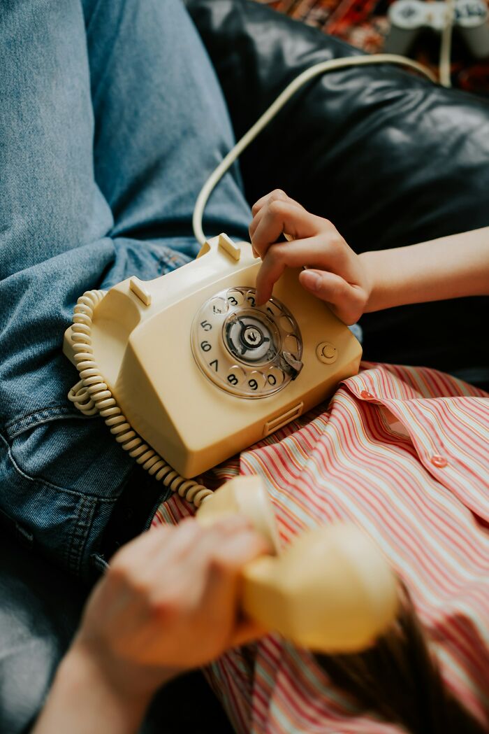 Child using vintage rotary phone, highlighting unique childhood joys that faded with smartphones and recorded life changes.
