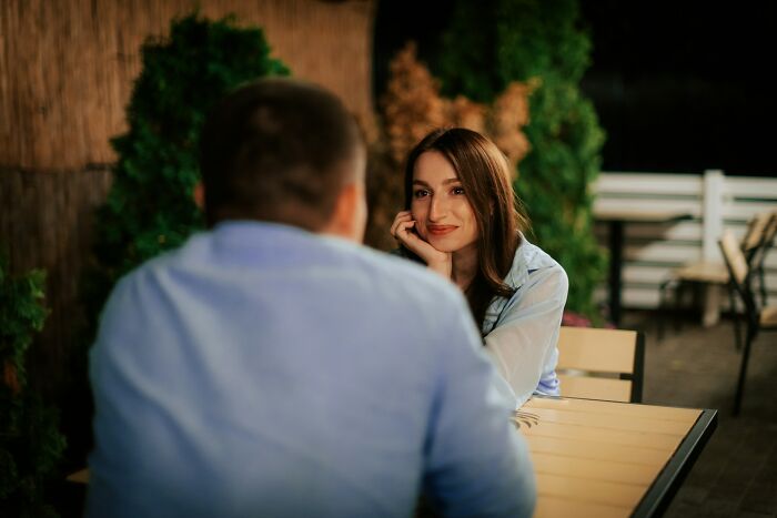 A woman smiling nervously at a man during an outdoor date, illustrating challenges of modern dating nightmare.