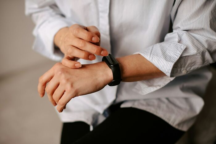 Person adjusting a black smartwatch on the wrist, one of the everyday items under $300 that improved lives.