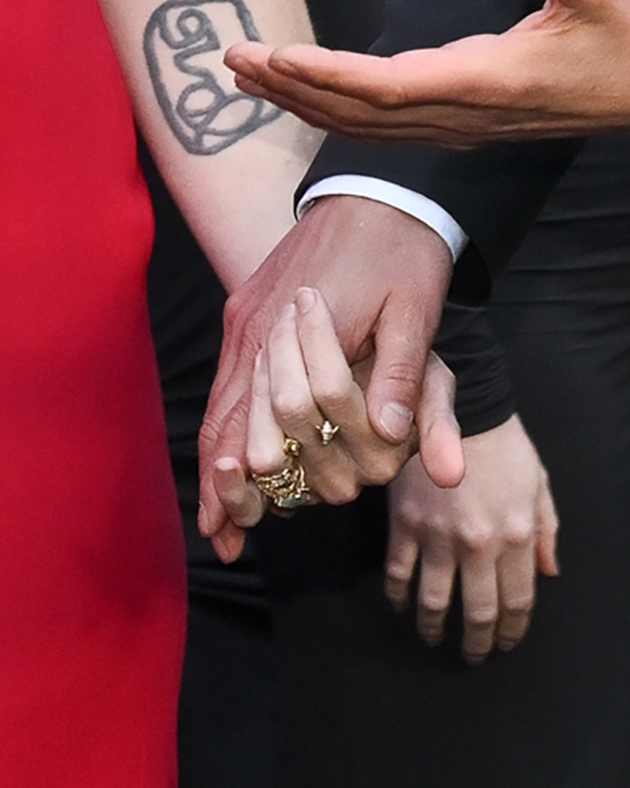 Keanu Reeves holding hands with girlfriend showing rings, sparking rumors of secret marriage after red carpet appearance.