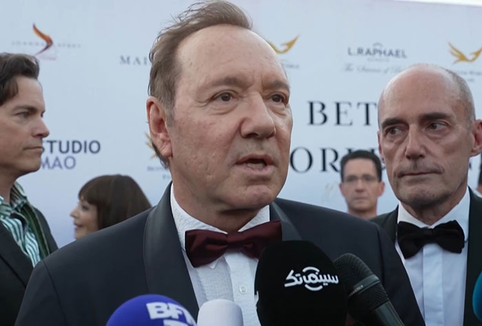 Kevin Spacey addressing media at red carpet event amid growing plastic surgery rumors and award reception.