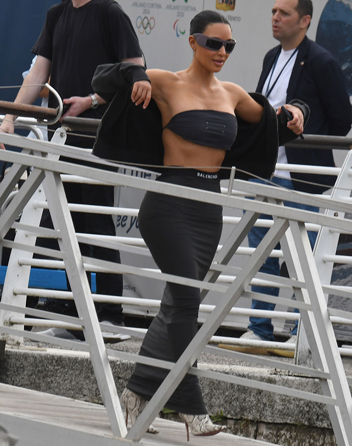 Kim Kardashian showing her tiny waist in a black outfit, sparking wild rib theory at Jeff Bezos wedding festivities.