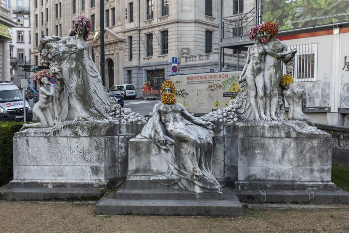 City statues dressed in colorful flowers by an artist, creating a magical floral urban art installation.