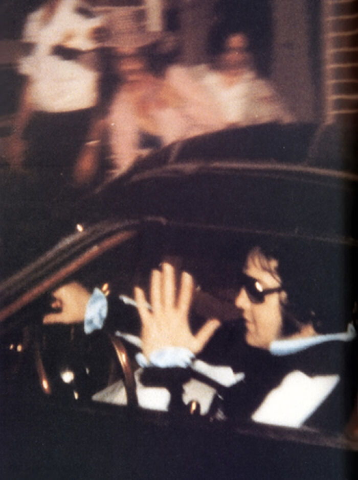 A famous person wearing sunglasses waves while sitting in a car in one of the last known photos.
