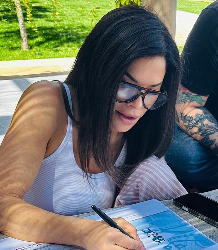 Woman wearing glasses writing at a table outdoors, with focus on details of Jeff Bezos' lavish wedding to Lauren Sanchez. Woman wearing glasses writing at a table outdoors, with focus on details of Jeff Bezos' lavish wedding to Lauren Sanchez.