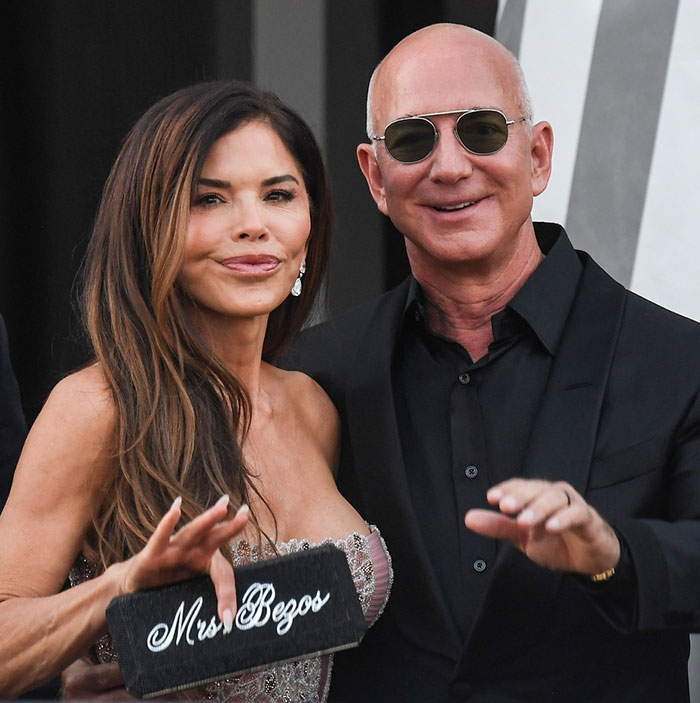 Woman holding a Mrs. Bezos clutch and man in sunglasses smiling, related to Jeff Bezos wedding ceremony reactions.