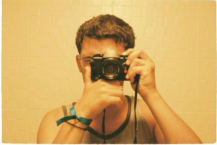 Person holding a vintage camera capturing a moment, reflecting unique childhood joys before smartphones changed recording habits