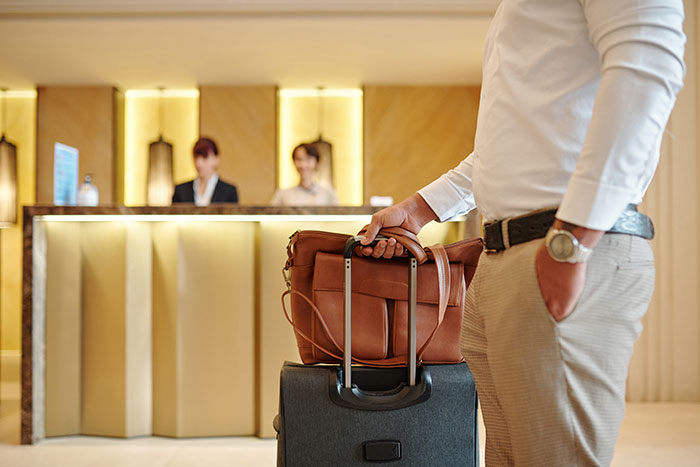 Hotel guest holding luggage at reception desk, highlighting interaction between entitled lawyer and hotelier over discounts. Hotel guest holding luggage at reception desk, highlighting interaction between entitled lawyer and hotelier over discounts.