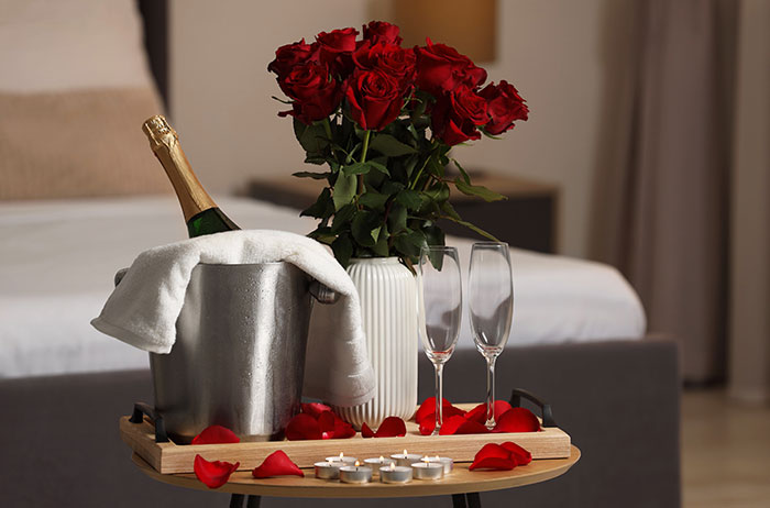 Romantic hotel setup with champagne, red roses, and candles symbolizing wedding celebration discounts request. Romantic hotel setup with champagne, red roses, and candles symbolizing wedding celebration discounts request.
