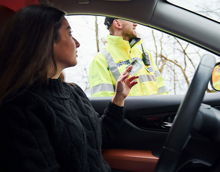 Woman in a car showing ID to a police officer outside, illustrating lawyers immediately knowing case outcomes.