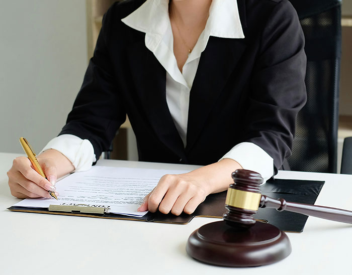 Lawyer reviewing legal documents at desk with gavel nearby, symbolizing case assessment and legal decisions.