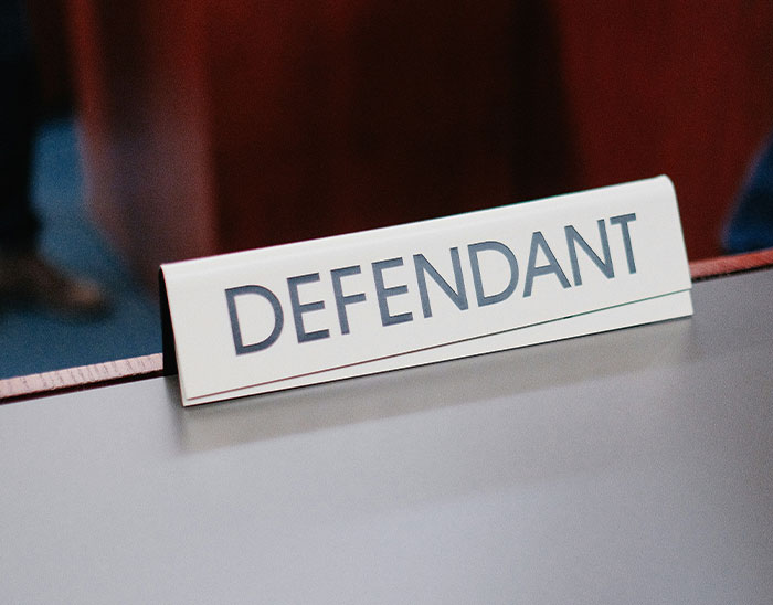 Defendant nameplate on a courtroom table representing a legal case with lawyers involved in the trial process.