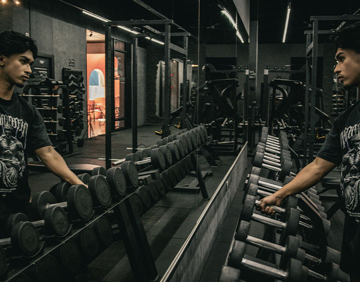 Young man in a gym selecting dumbbells with focused expression, representing lawyers and case outcomes concept.