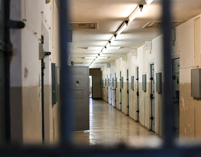 View of a dimly lit prison hallway with closed cell doors, symbolizing lawyers and legal cases.