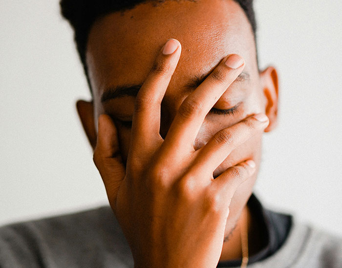 Man covering his face with his hand, expressing frustration and disappointment related to lawyers and losing a case.