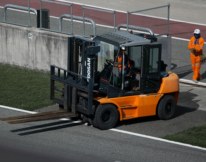 Forklift in use at industrial site with workers nearby, illustrating lawyers and case-related labor scenario.