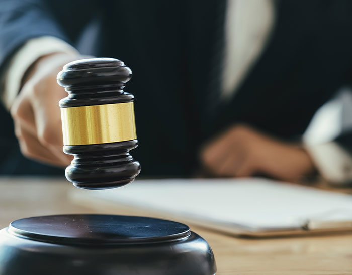 Judge’s gavel striking sound block in courtroom, symbolizing lawyers and legal case decisions.