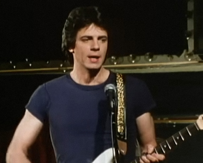 Famous 80s rockstar performing on stage playing guitar, showcasing energetic and iconic musical presence.