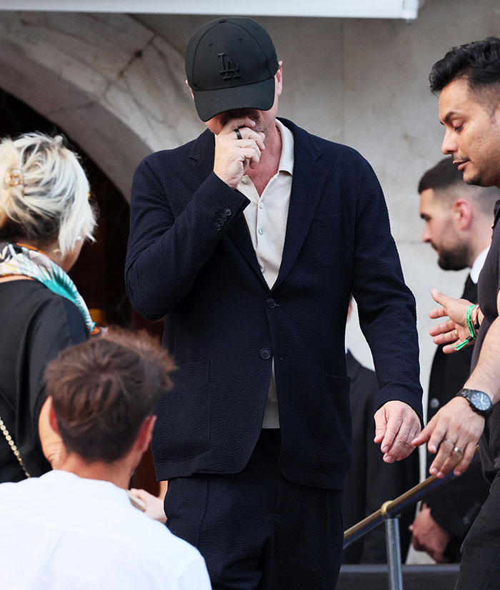 Man in a black suit and cap among guests at a celebrity event in Venice for a high-profile wedding welcome party.