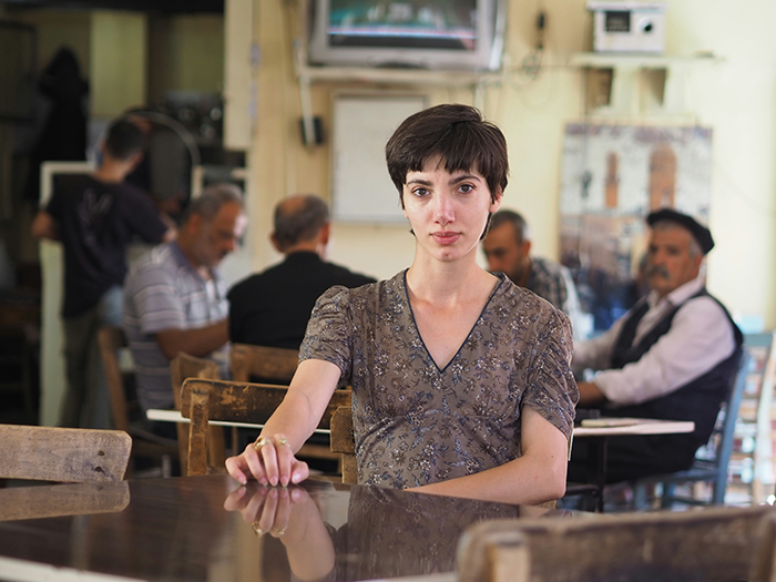 Young woman sitting alone at a table in a cafe, reflecting tension after a difficult family dinner about her older relationship. Young woman sitting alone at a table in a cafe, reflecting tension after a difficult family dinner about her older relationship.