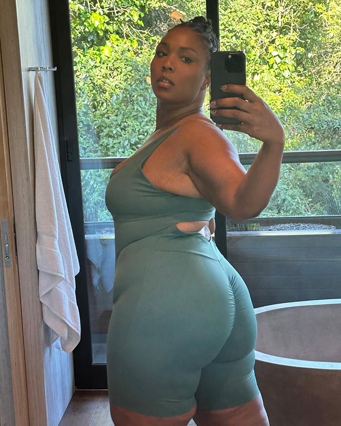 Lizzo taking a mirror selfie in green workout outfit, addressing rumored Ozempic use and weight-loss method.