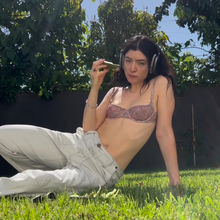 Lorde lounging outside wearing headphones and a bra, related to vinyl release and x-rated image discovery by fans. Lorde lounging outside wearing headphones and a bra, related to vinyl release and x-rated image discovery by fans.
